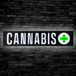 cannabis LED sign lit up against a black brick wall