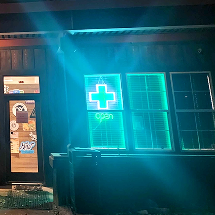 Dispensary Green Cross LED window sign inside a Colorado cannabis dispensary being lit up at night