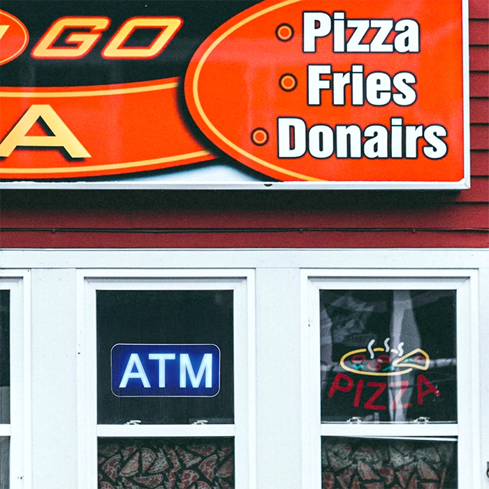 Pizza shop with an LED ATM sign hung in the window next to another window with a Pizza LED Neon sign