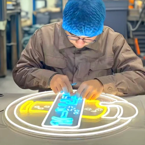 Brite-Ideas-Custom-Signs-Engineered-Engineer-Building-Sign-700x700-02 A man is customizing a neon sign in a factory for signage engineering.