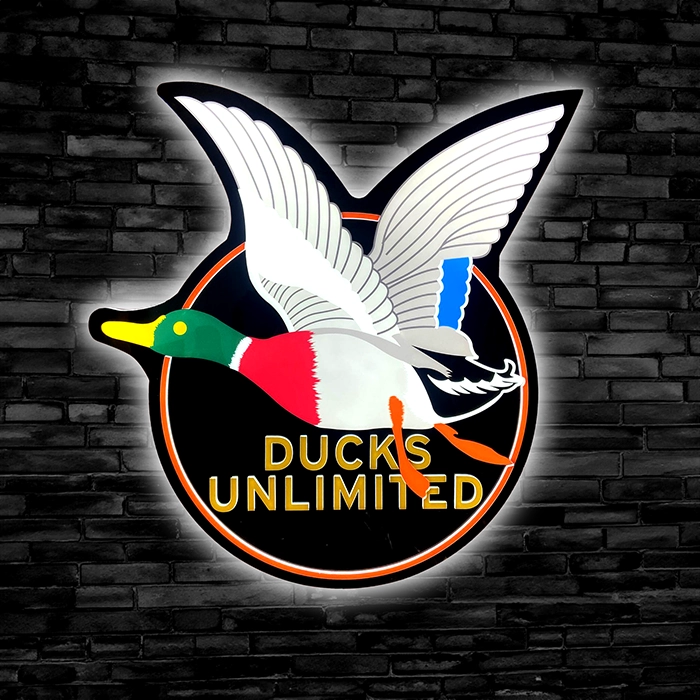 Ducks unlimited logo displayed on a black brick wall.
