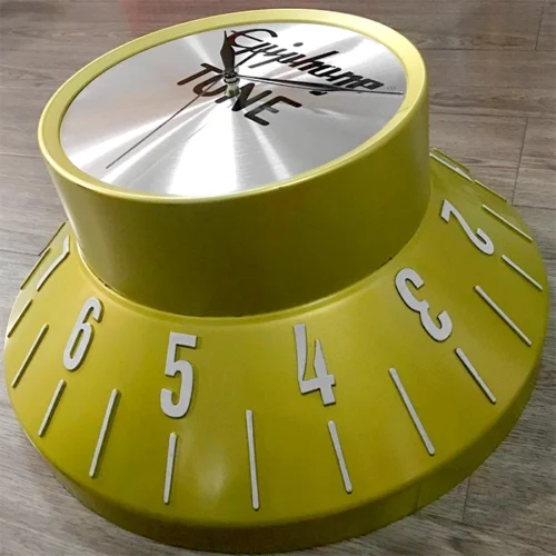 A yellow clock on a wood floor.