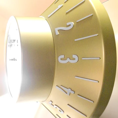 A gold non-illuminated clock on a wall.