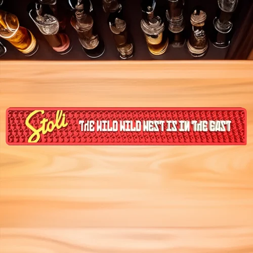 A red Stoli Vodka bar mat with white non-illuminated text on it next to a row of bottles.