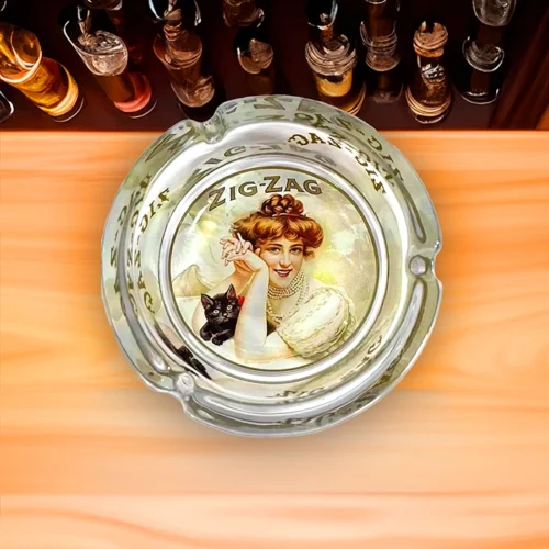 A Zig Zag glass ashtray with a picture of a woman and a cat, perfect for non illuminated signs.