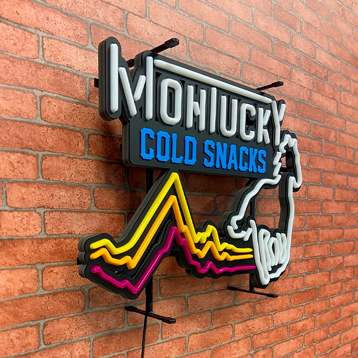 A colorful custom led neon sign reading "mohiucky cold snacks" mounted on a brick wall, featuring stylized graphics and bright neon-like lines.
