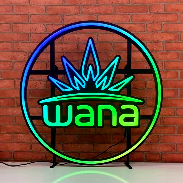Neon sign featuring the word "wana" in green with a blue crown design, set against a brick wall background. This custom led neon sign adds a vibrant touch to any space.