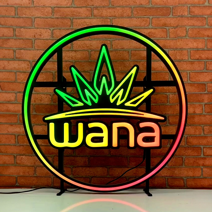 Color changing motion LED neon sign with the word "wana" inside a circular frame, featuring a crown design on top, displayed against a brick wall.