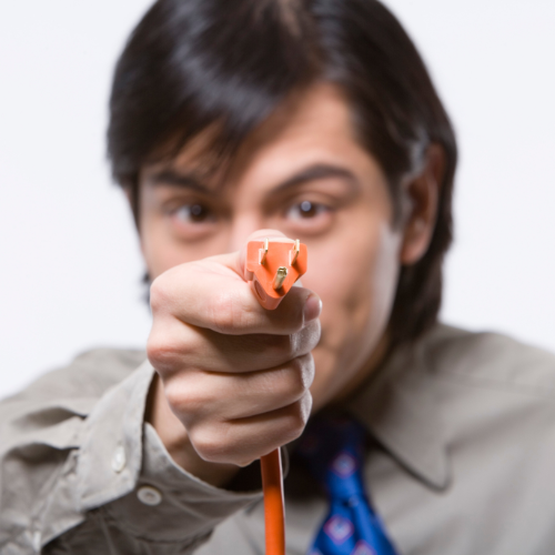 A dark haired man holds a close up shot of a Power Supply Cord up in front of his face.